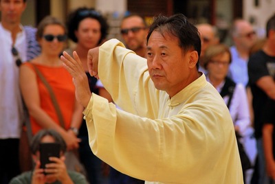 Praticante de Tai-Chi-Chuan ao ar livre, rodeado por observadores
